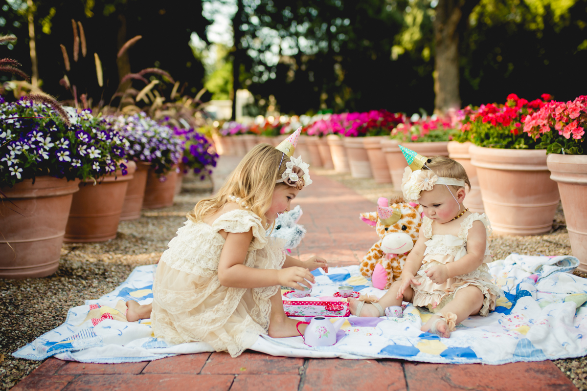 A girl pours tea for her little sister during their tea party photo shoot at the CSU Trial Flower Gardens in Fort Collins
