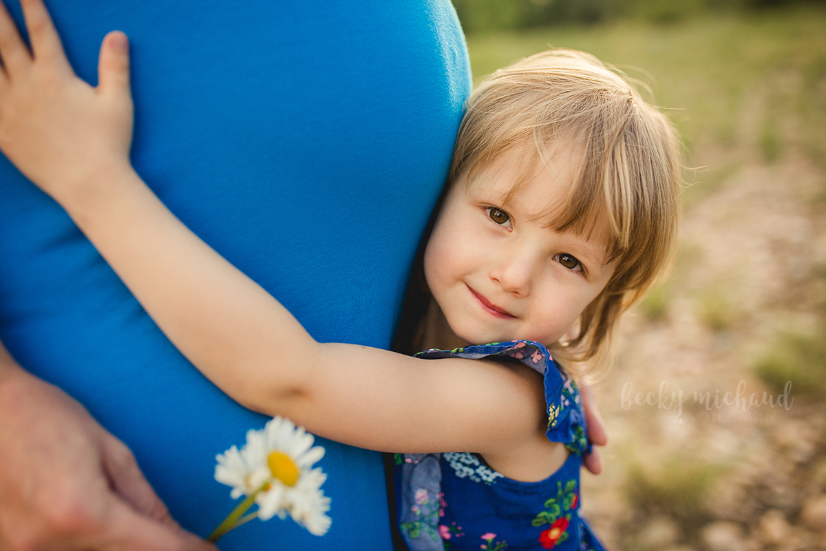 A little girl hugs her mom's belly during their Fort Collins maternity photo session