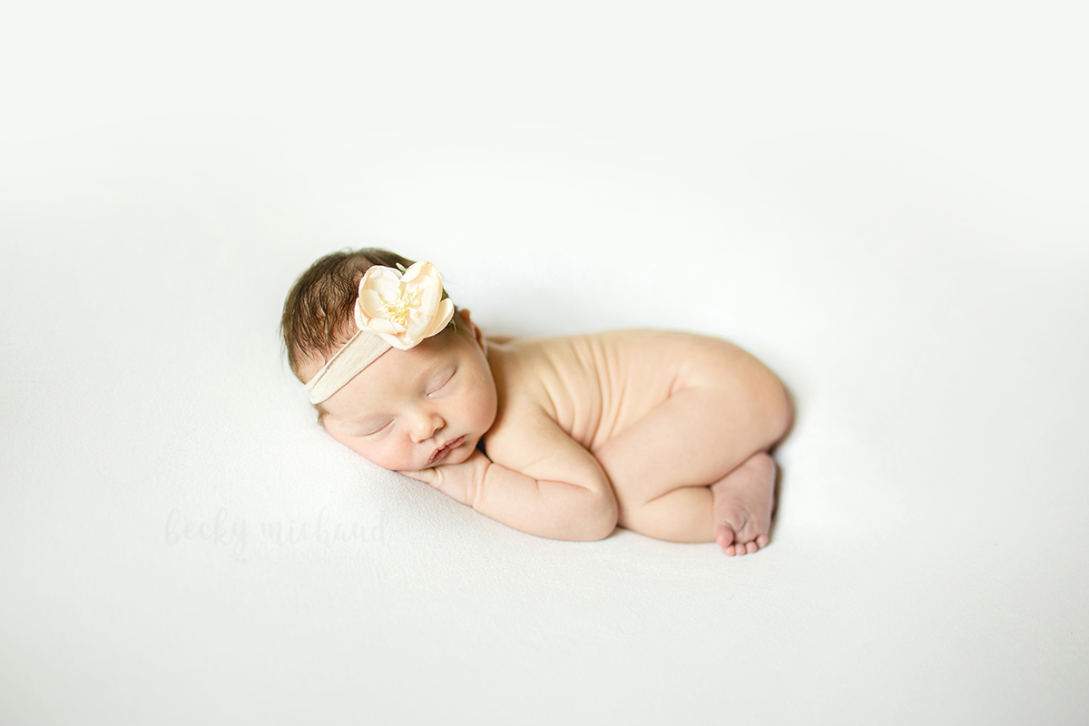 Simple and natural newborn photo of a baby girl wearing a floral headband