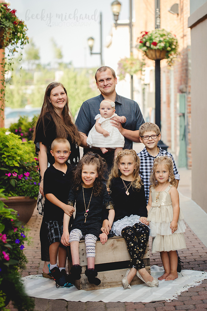 A family of 8 poses for a family photo in an alley in Old Town Fort Collins
