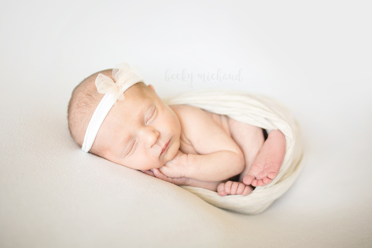 Baby smiling during her in home newborn session in gray and white