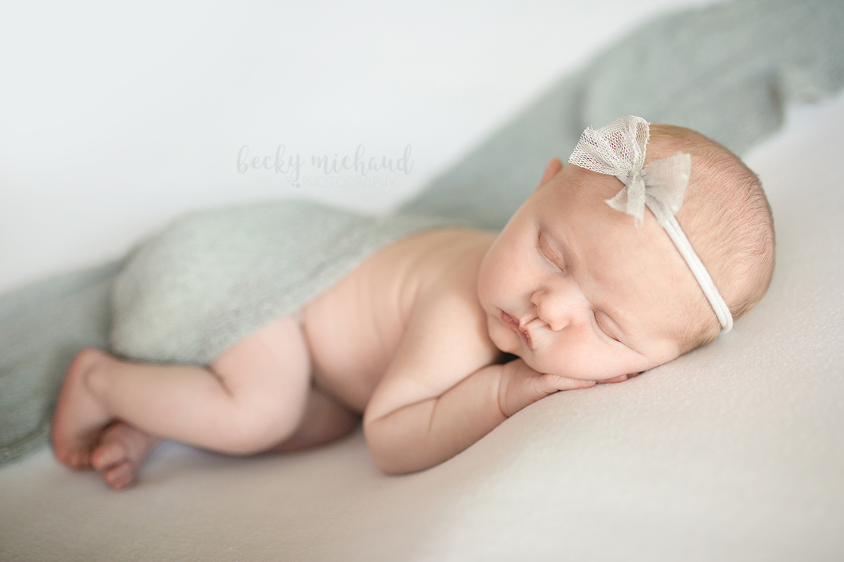 In her home in Fort Collins, a baby girl poses in white and gray for her newborn portraits