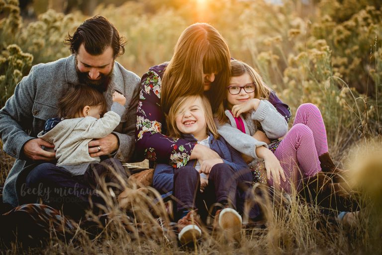 A family laughs together in a field at a Fort Collins Natural Area during their family photo session
