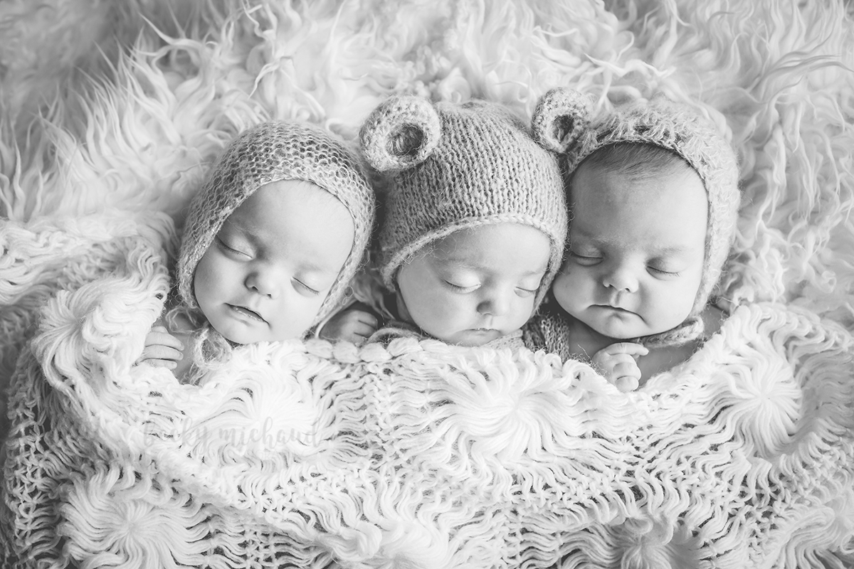 Black and white photo of triplet girls tucked under a blanket taken by Becky Michaud, Fort Collins photographer