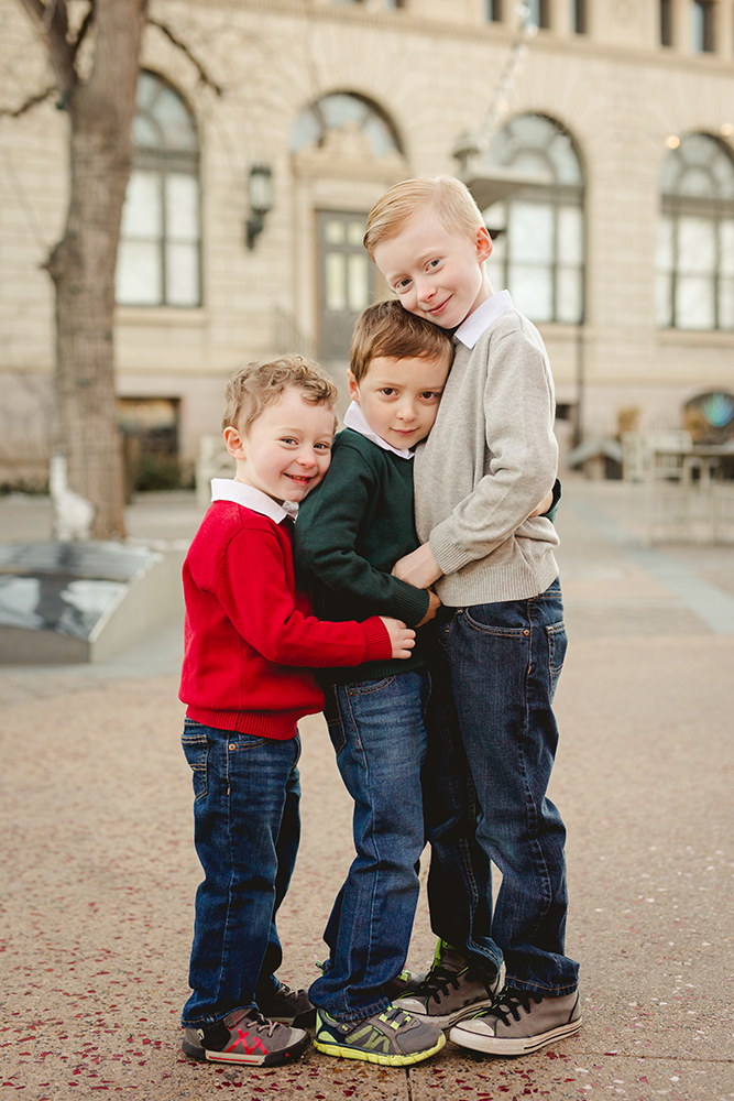 Three brothers hug each other during their photo shoot at Oak Street Plaza in Old Town Fort Collins
