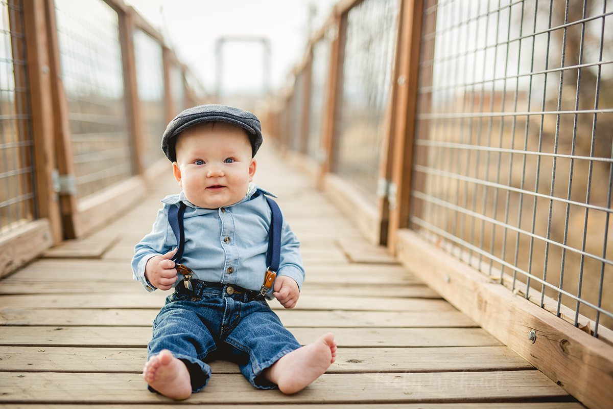 A baby sits on bridge in Fort Collins during his one year photo shoot