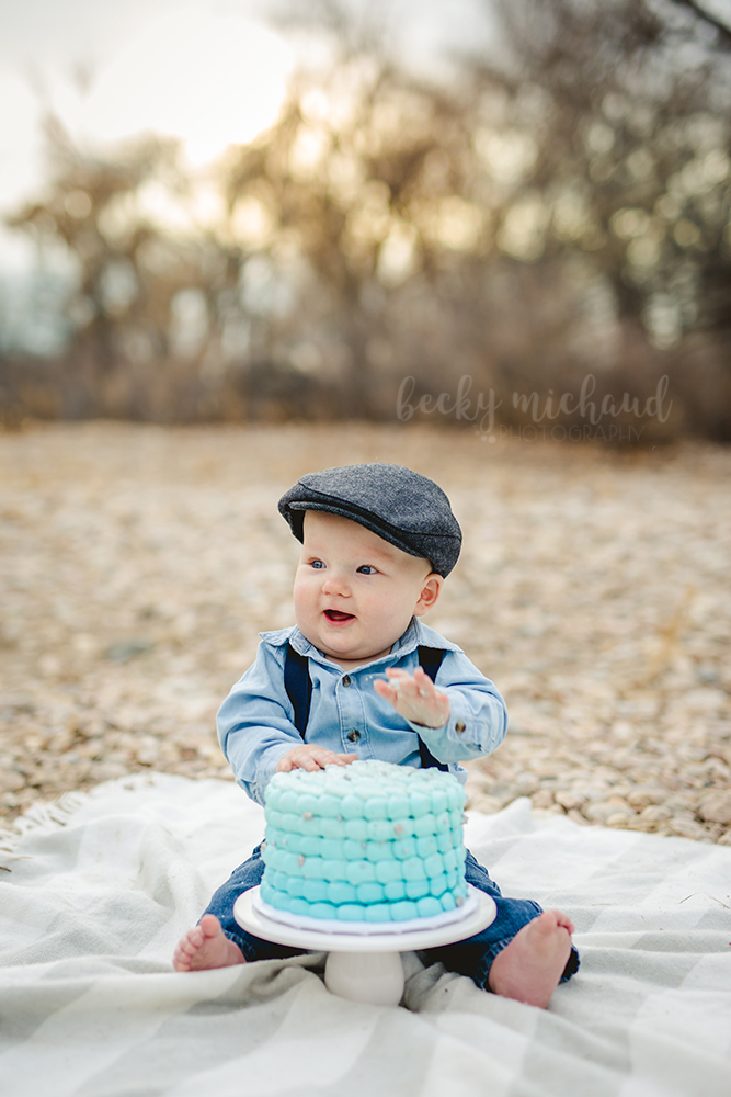 A happy baby plays with his cake at his Fort Collins cake smash photo session
