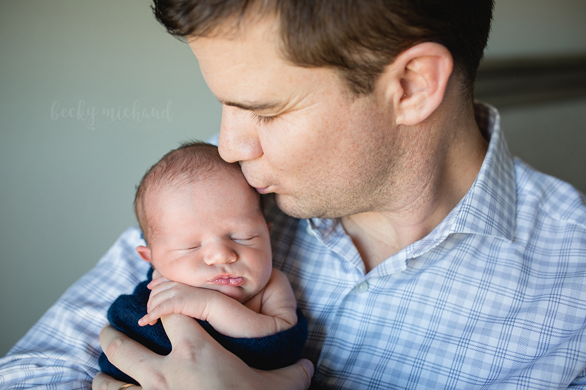 A dad kisses his newborn baby boy in a photo taken by Becky Michaud, Northern Colorado newborn photographer