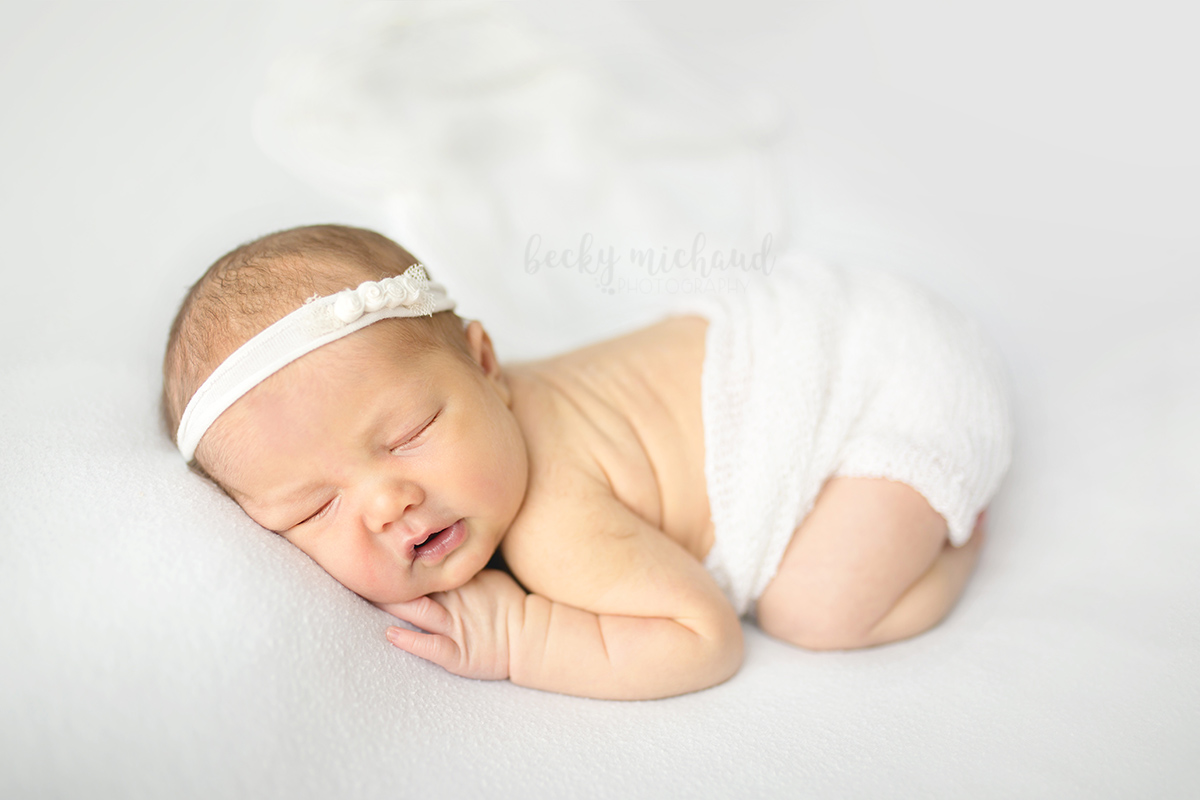 Simple white photo of a newborn girl taken during her in-home posed newborn photo session in Loveland, Colorado