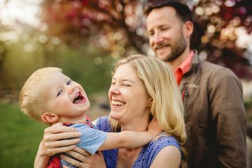 A little boy laughs with his parents as they play at Benson Sculpture Park in Loveland Colorado