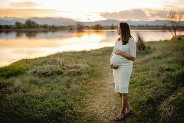 An expectant mom gazes out over the lake in a maternity portrait taken by Becky Michaud, Fort Collins photographer