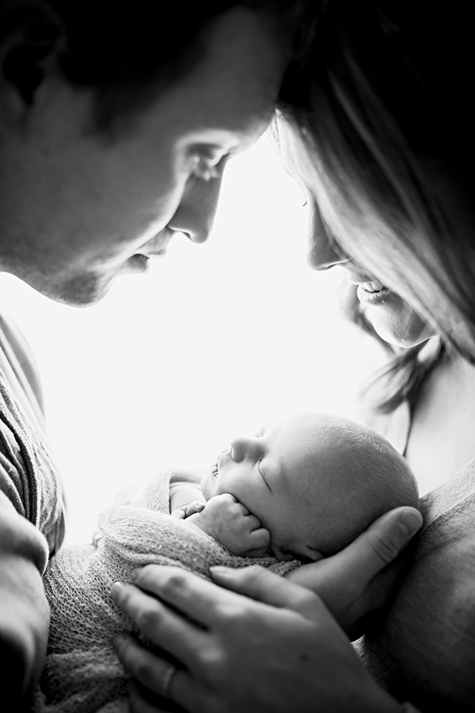 black and white backlit photo of a mom and dad with their newborn boy in their Fort Collins home