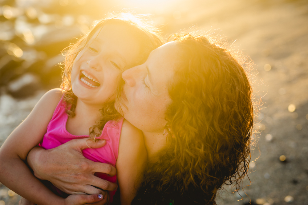 Photo of a mom kissing her daughter's cheek in the golden sunlight