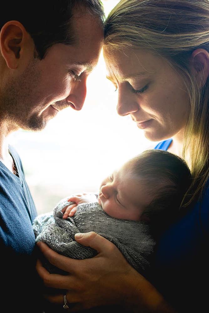 New parents gaze at their baby boy during their newborn photography session in their home in Northern Colorado