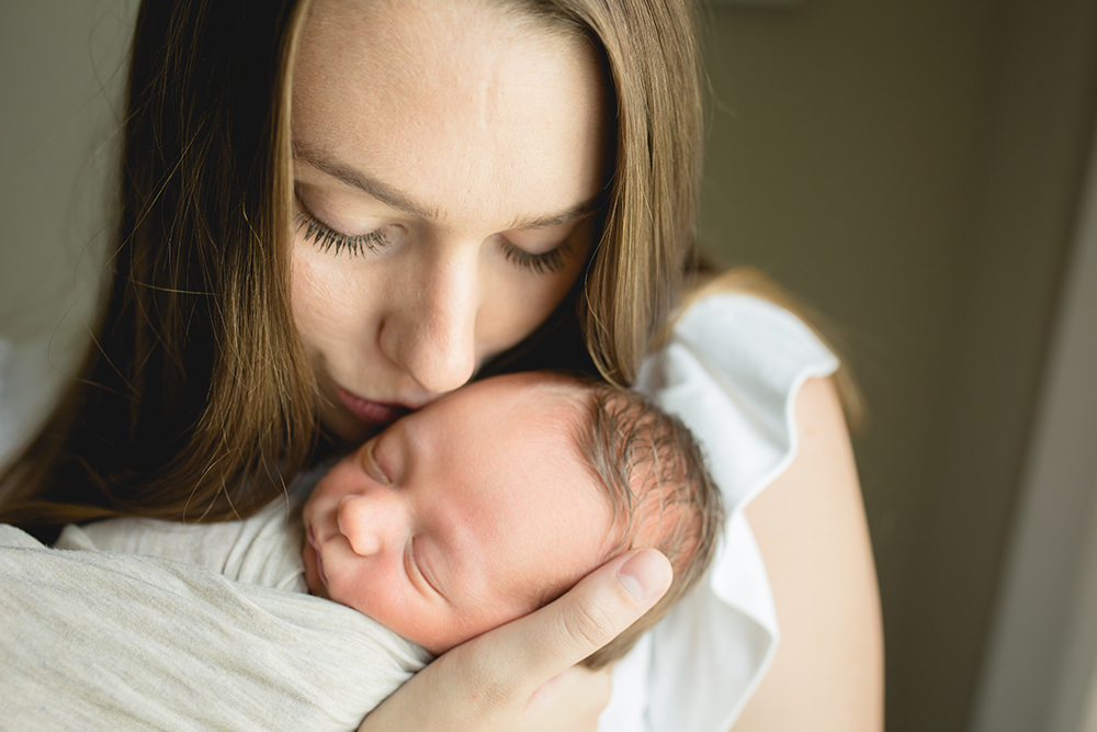 mom kisses her baby boy in a photo taken as part of their newborn photography session in their home in northern Colorado