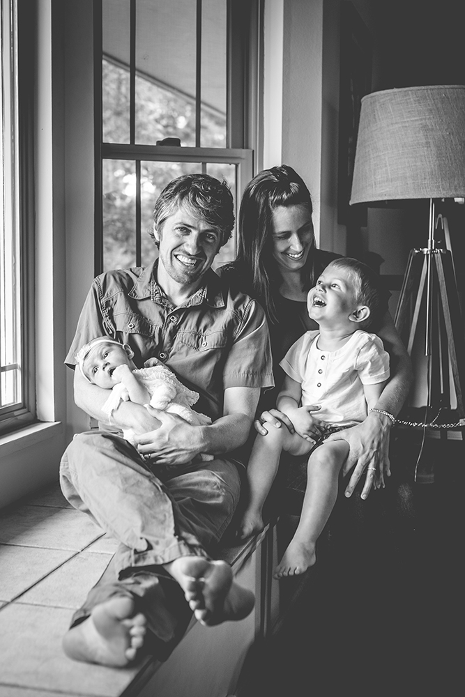 black and white lifestyle photo of a family sitting in their Fort Collins home with their newborn girl