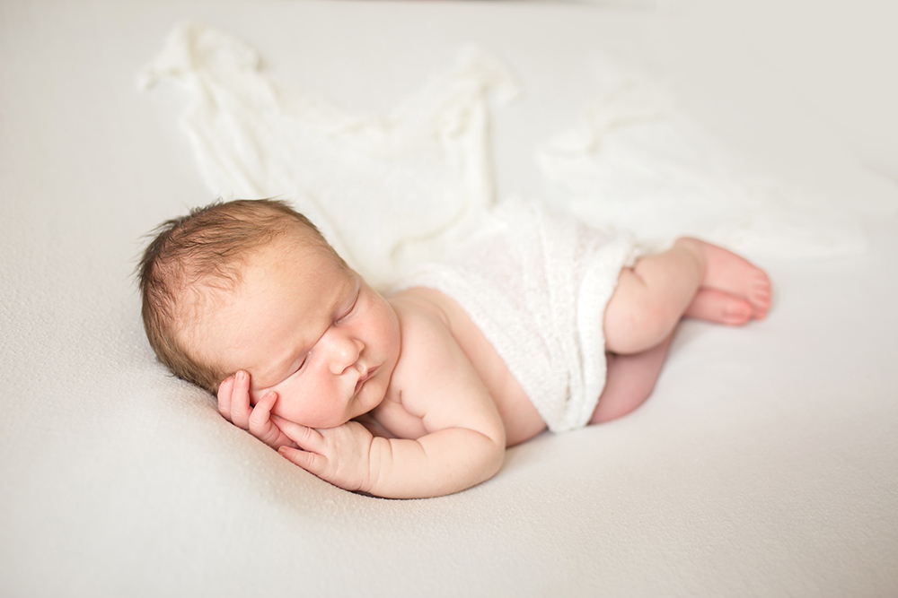 Simple natural newborn photo of a baby in white taken in his Fort Collins home