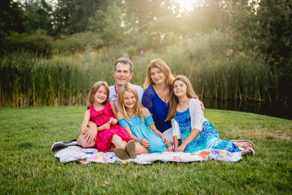 A family of five poses for a photo in front of a pond in Loveland, Colorado