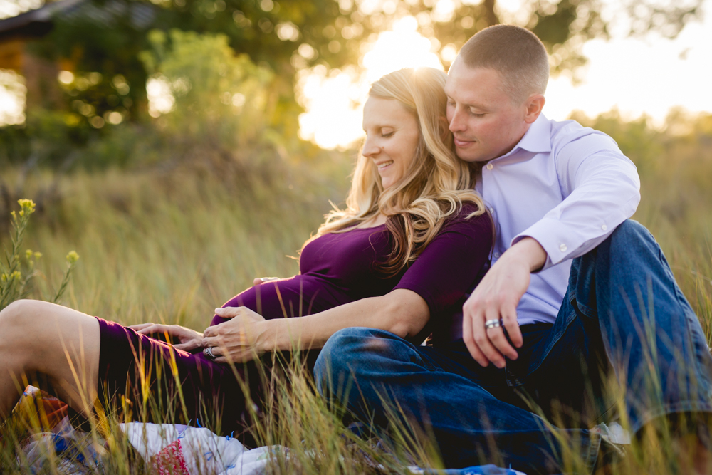 A couple cuddles together as they take their maternity photos at a Loveland, Colorado park