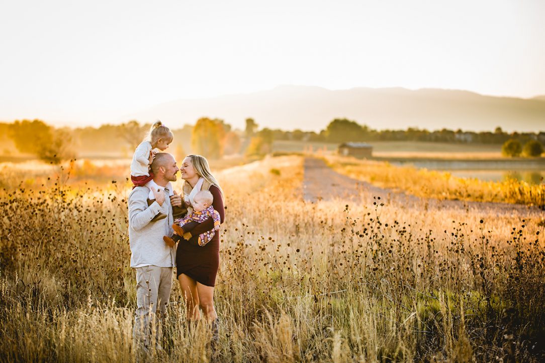 A family stands in a field together in east Fort Collins as the sun sets over the Colorado foothills