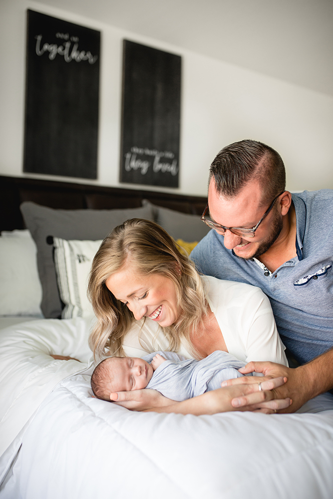 A family of three snuggles together during their in home newborn lifestyle session in Fort Collins