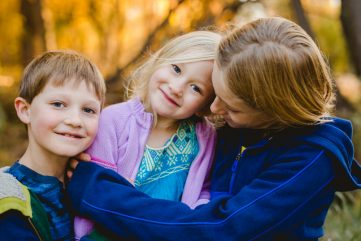 Three siblings play together during their family photography session in the fall in Fort Collins