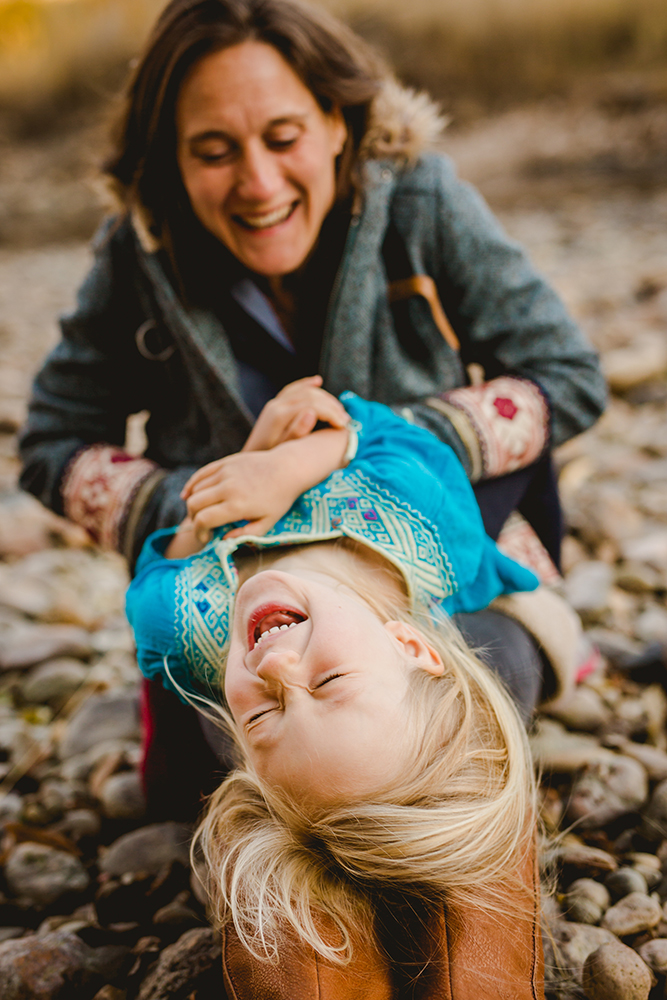 A mom tickles her daughter as the girl laughs in a photo taken by Becky Michaud, Fort Collins photographer for families