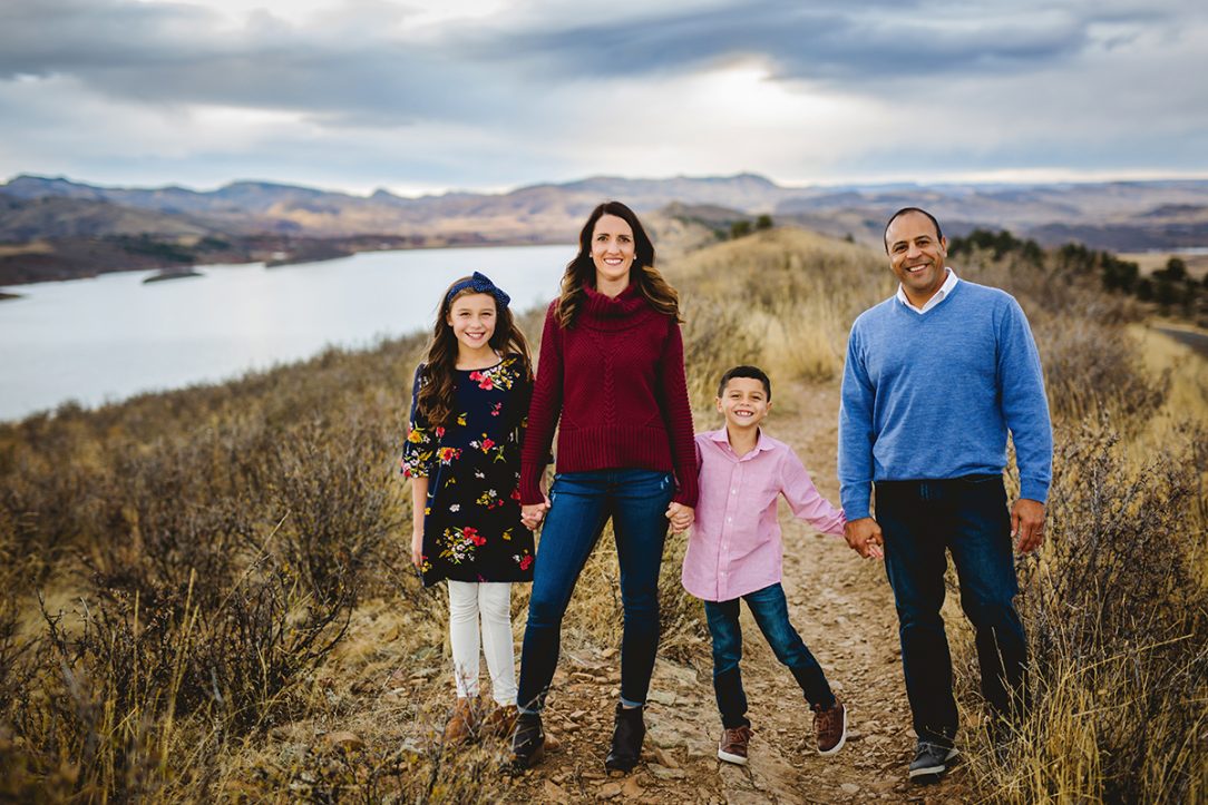 A family of four stands on a ridge at Horsetooth Reservoir during their photography session