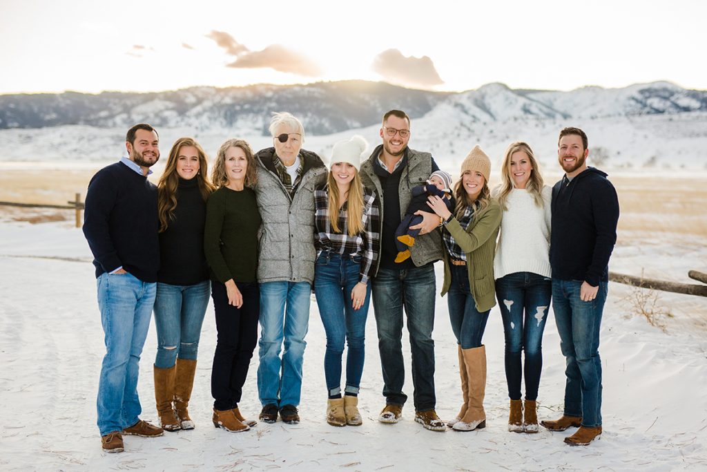 An extended family poses in front of the snowy Colorado foothills for their family photos