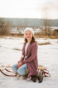 A girl sits on an antique sled as she poses for a portrait in Fort Collins, Colorado