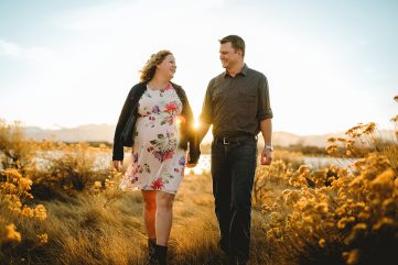 Maternity photo of a couple walking in a field together in Loveland Colorado