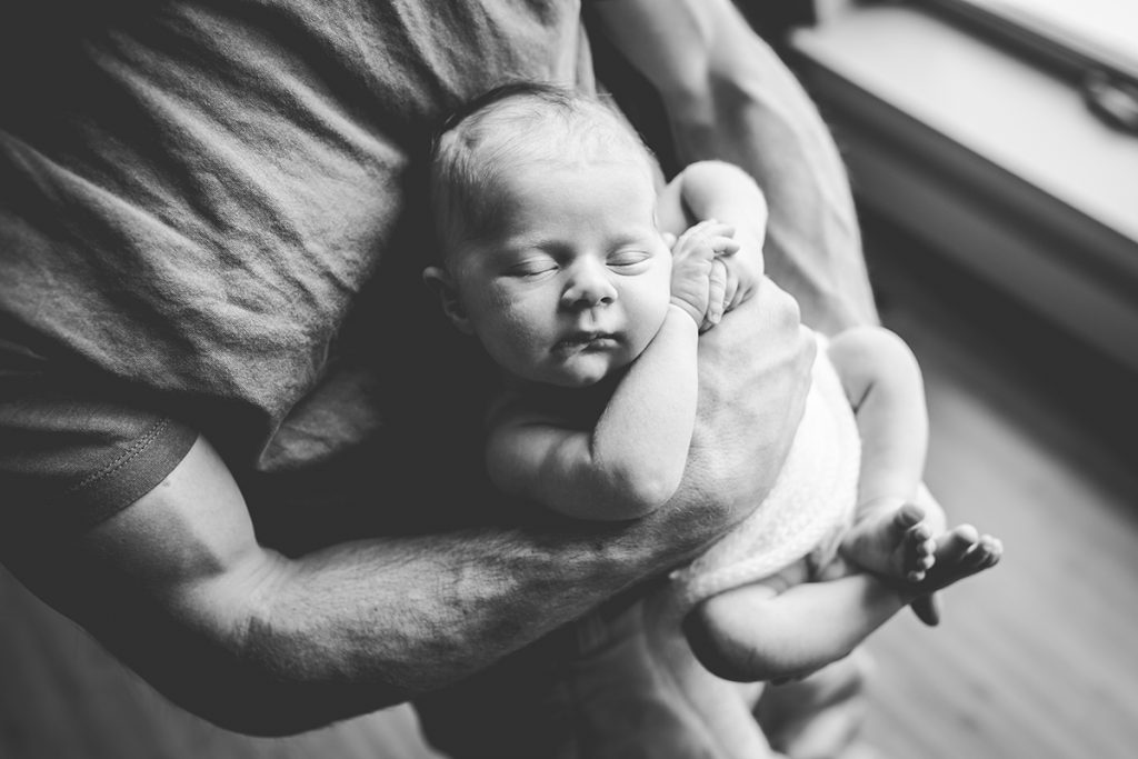 black and white photo of a newborn sleeping in her dad's arms taken by Becky Michaud, Fort Collins photographer