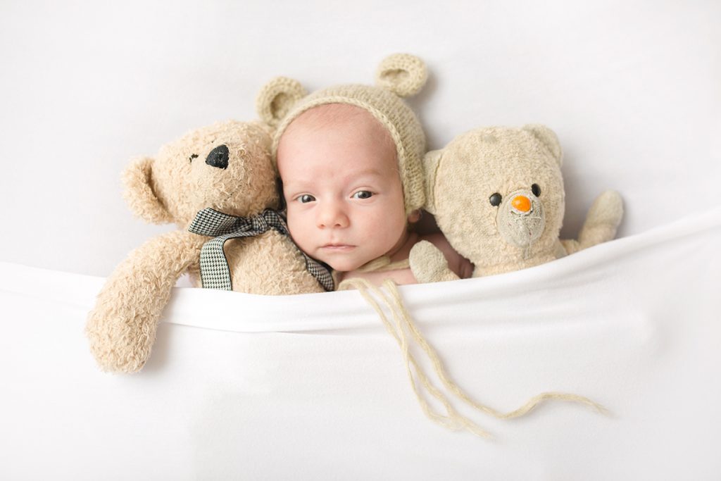Baby boy tucked in with teddy bears in a newborn photo taken in his Fort Collins home
