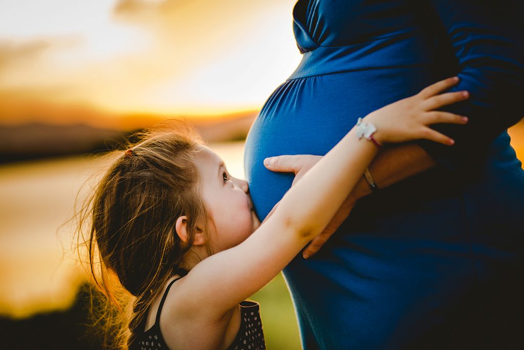A little girl kisses her mom's belly in a maternity photo taken by Becky Michaud, Fort Collins photographer