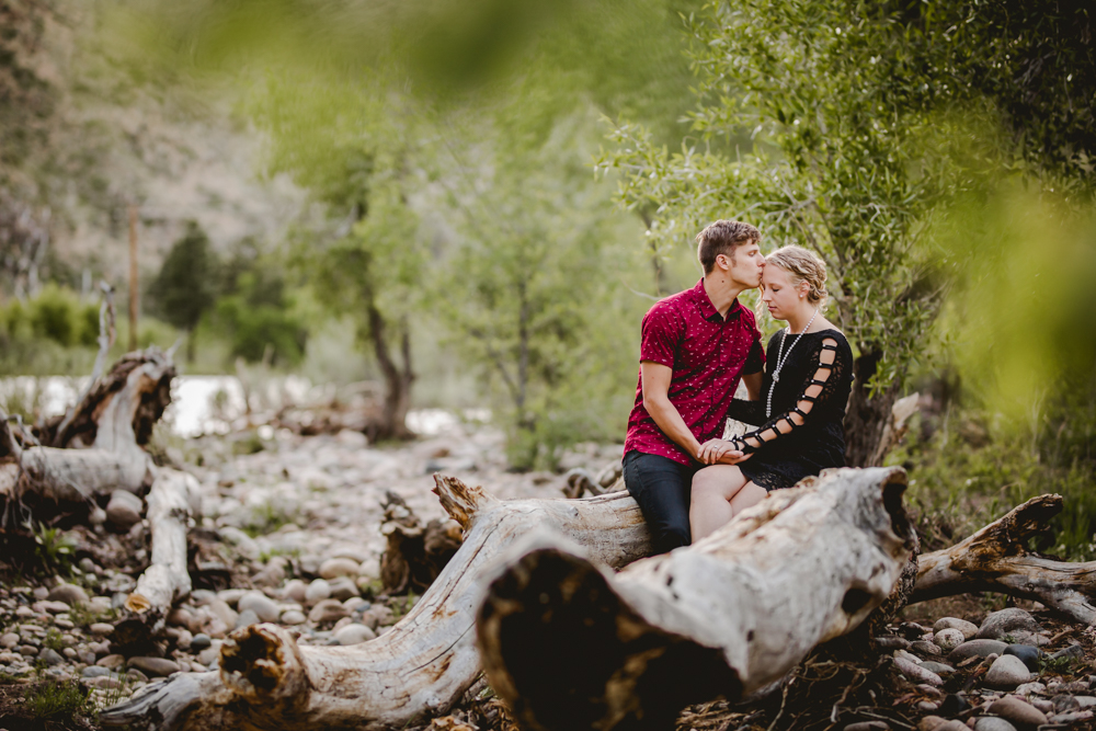 Couple sitting on a log by the river in a photo taken by Becky Michaud, Fort Collins photographer