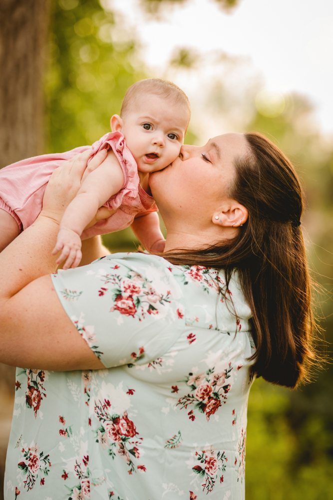 A mom kisses her baby girl during their family photo session in Loveland Colorado