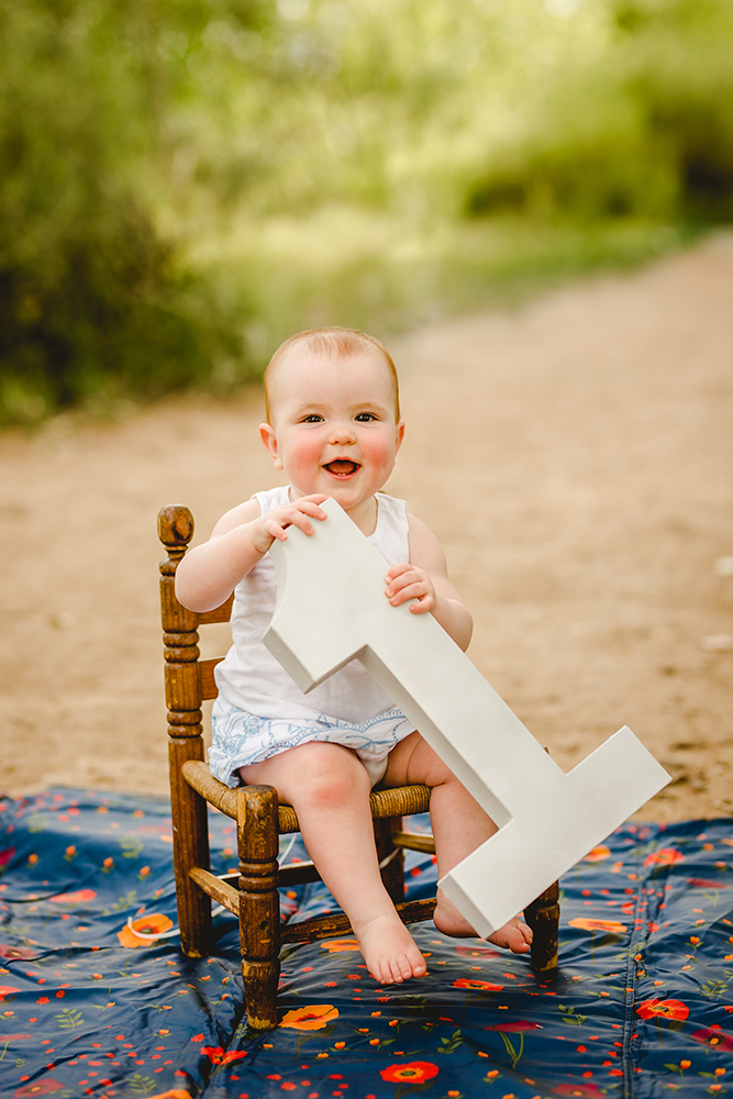 One year old girl poses with a giant number one at a natural area in Fort Collins