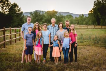 Photo of an extended family posing by a fence in front of the foothills of northern Colorado