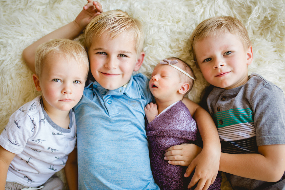 three brothers pose with their new baby sister during her newborn photography session in northern Colorado
