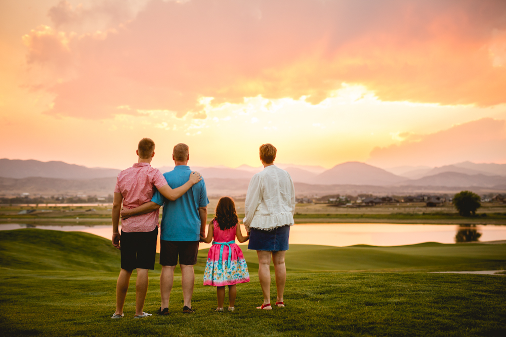 A family watches the sun set over the mountains during their family photo session in Berthoud, Colorado