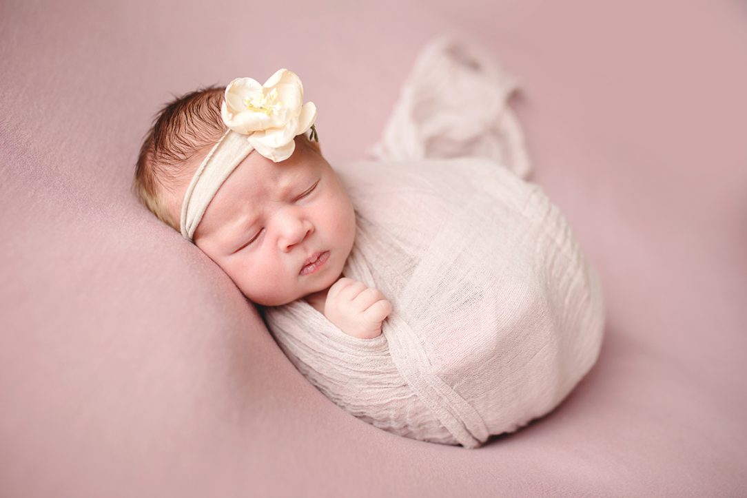 Photo of a baby on a pink blanket taken in her Fort Collins home during her newborn photo shoot