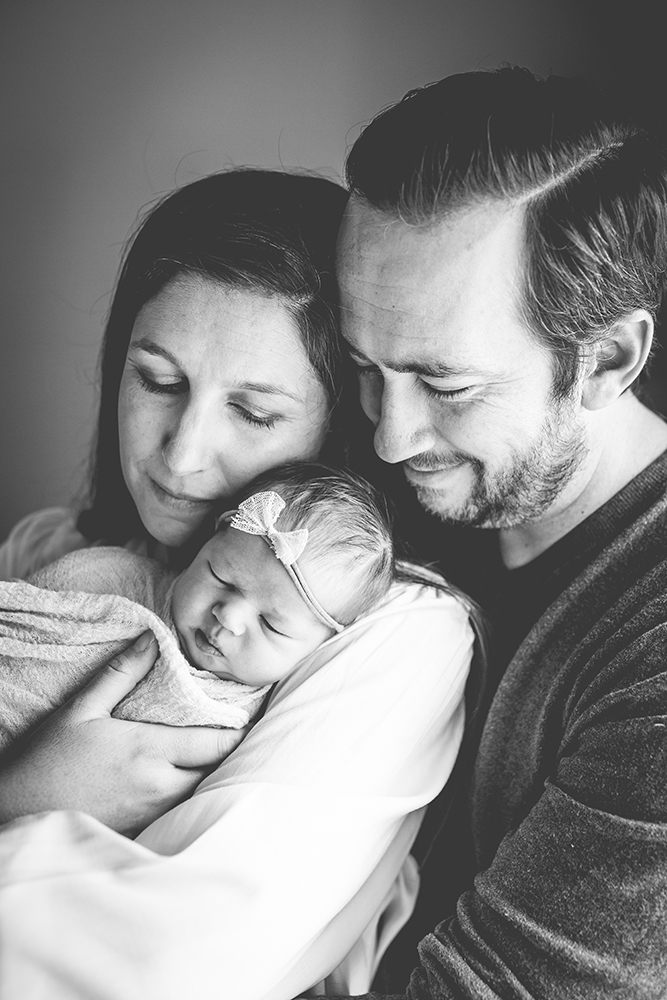 Monochrome photo of a mom and dad holding their baby girl in their Fort Collins home