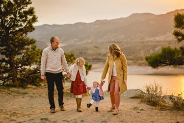 A family walks together as the sun sets over Horsetooth Reservoir behind them