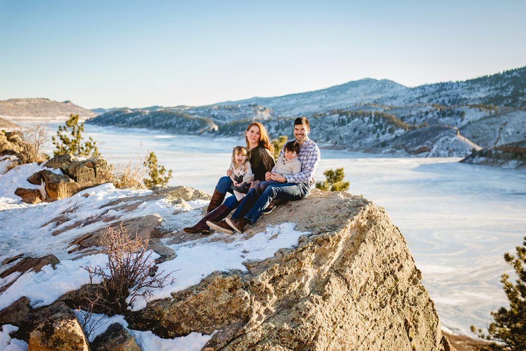 Family of four poses for a photo at Horsetooth Reservoir in the snow