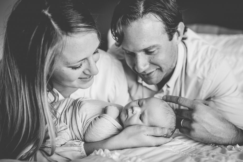 Black and white photo of parents holding their newborn baby boy in their home in Colorado