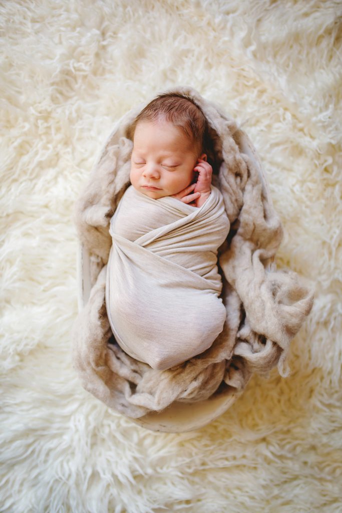 Newborn photo from an in home newborn session of a baby in a white bowl