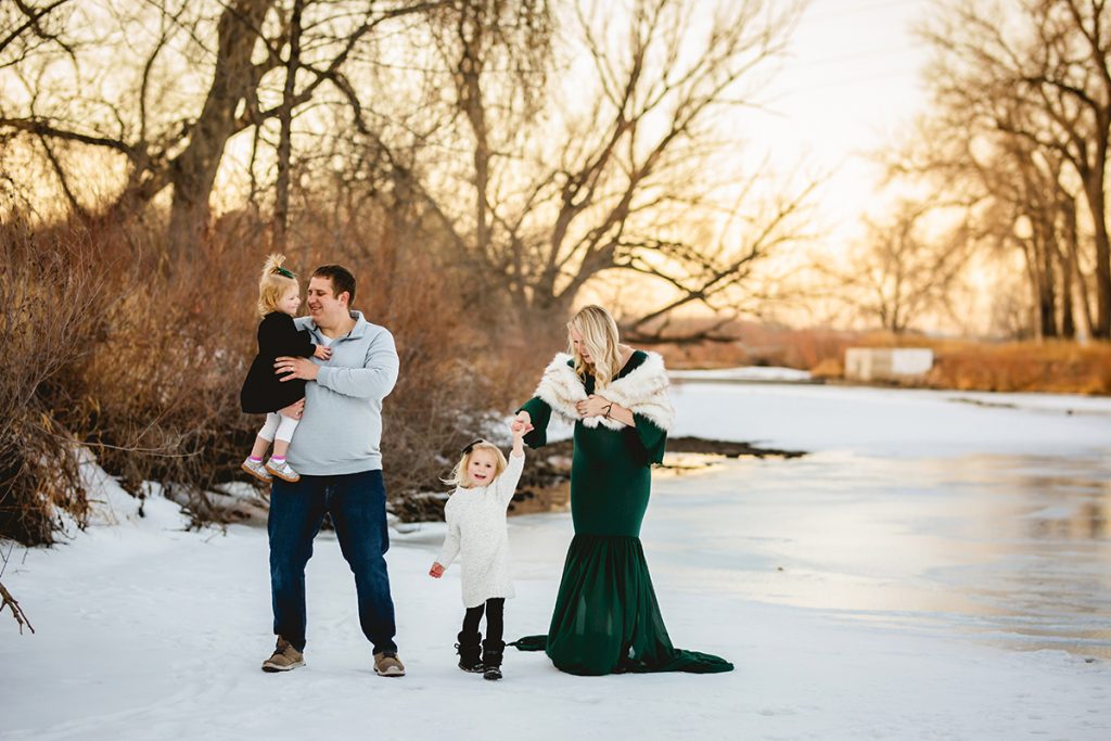 A family plays together in the snow in a maternity photo session in Fort Collins Colorado