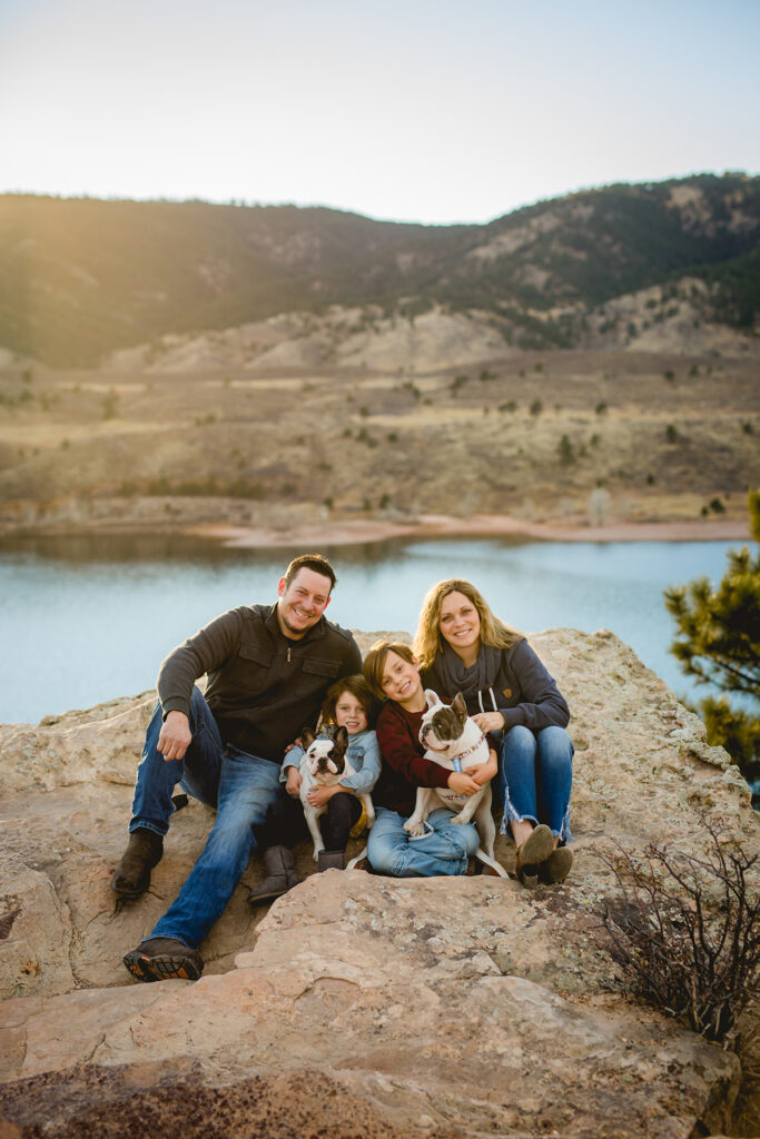 A family sits ona rock at Horsetooth Reservoir with their two dogs