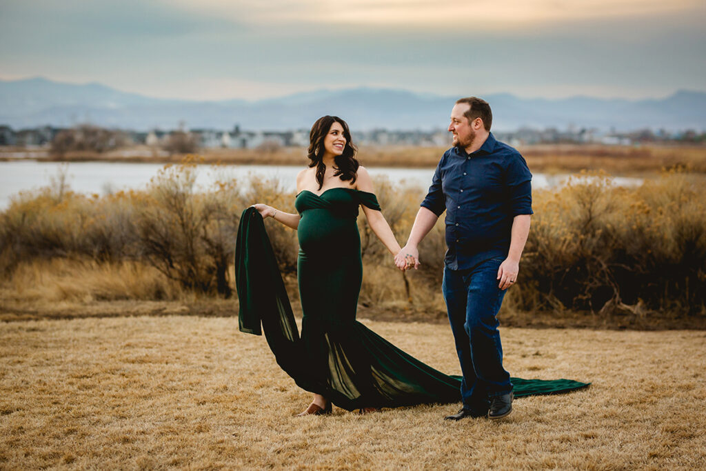 Maternity photo of a man and woman walking through a field taken by Fort Collins photographer Becky Michaud 