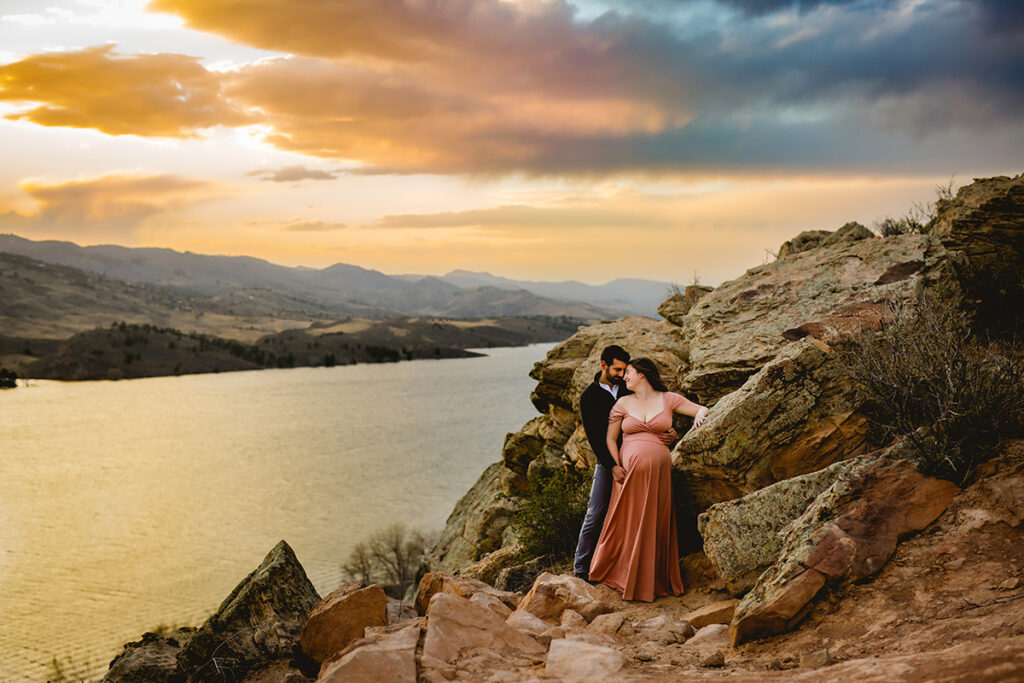 A couple poses by the rocks at Horsetooth Reservoir for their maternity photography session